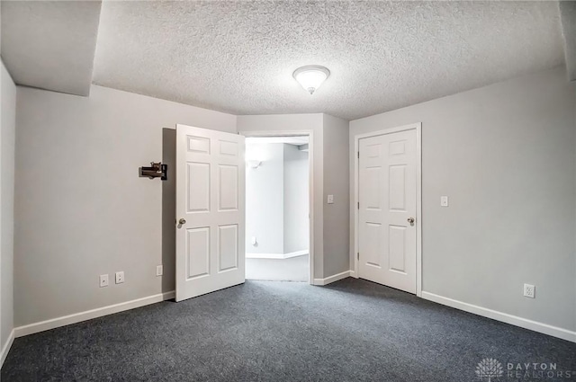 unfurnished bedroom with dark colored carpet, baseboards, and a textured ceiling