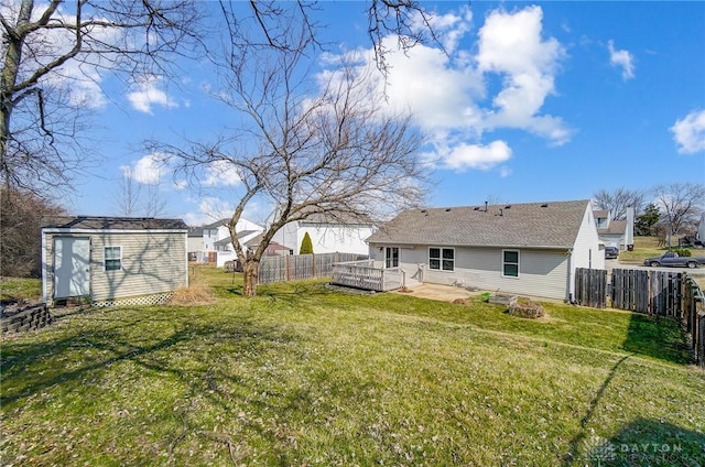 view of yard with a fenced backyard, a wooden deck, an outdoor structure, and a shed