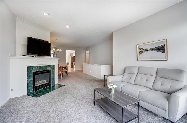 living room featuring carpet, baseboards, recessed lighting, a tiled fireplace, and a notable chandelier