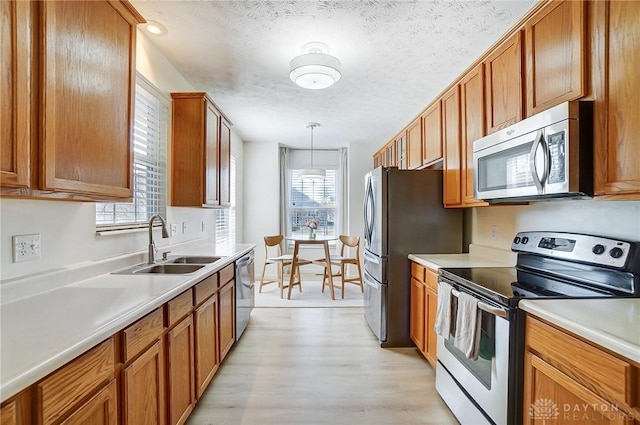 kitchen with a sink, plenty of natural light, appliances with stainless steel finishes, and brown cabinetry