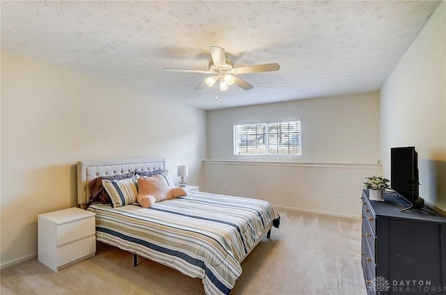 bedroom with baseboards, light carpet, a textured ceiling, and a ceiling fan