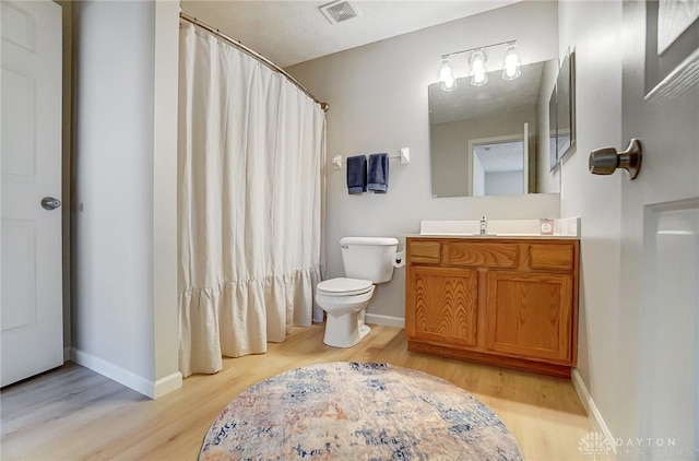 bathroom featuring visible vents, toilet, baseboards, and wood finished floors