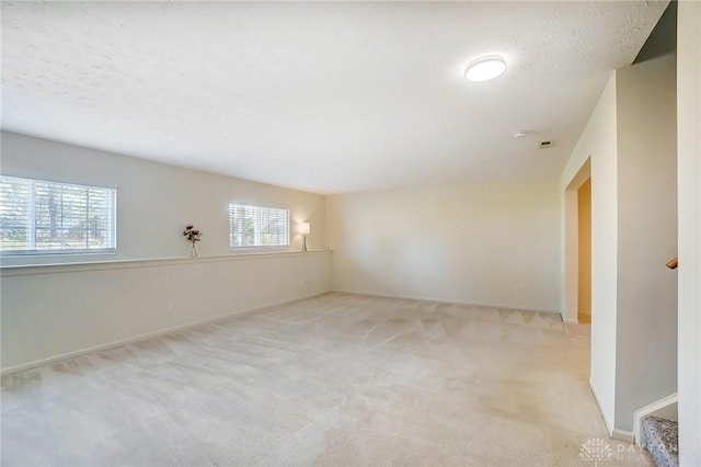 spare room featuring a textured ceiling, stairs, baseboards, and carpet floors