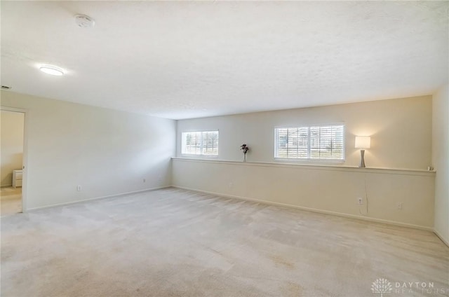 spare room with baseboards, a textured ceiling, and carpet flooring