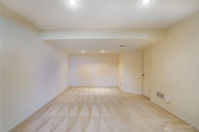 unfurnished room with visible vents, light carpet, and baseboards