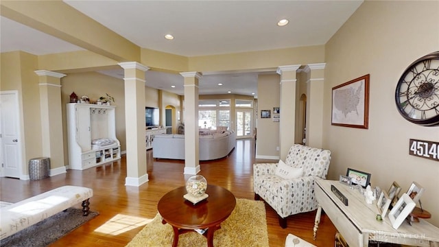 living area featuring recessed lighting, baseboards, ornate columns, and wood finished floors