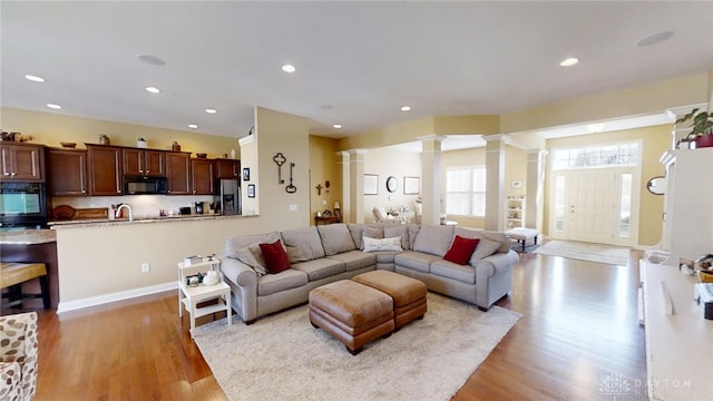 living area with recessed lighting, ornate columns, and wood finished floors