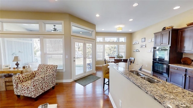 kitchen with light stone countertops, recessed lighting, a sink, dark wood-type flooring, and dobule oven black