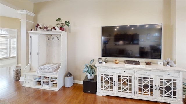 living area with decorative columns, wood finished floors, and baseboards