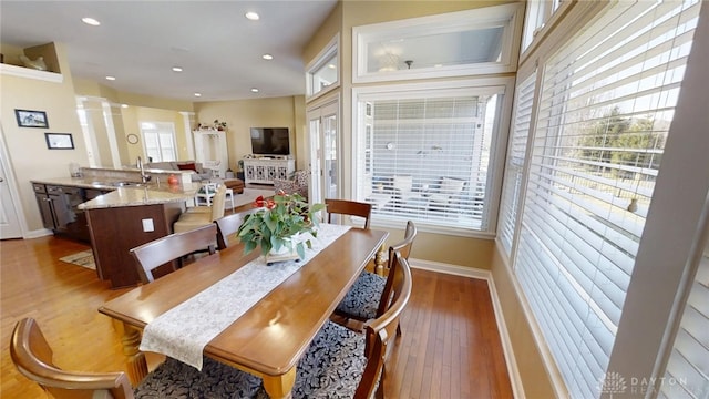 dining space with wood finished floors, recessed lighting, baseboards, and ornate columns