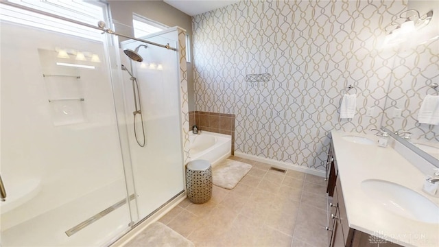 full bathroom with wallpapered walls, a shower stall, double vanity, and a sink