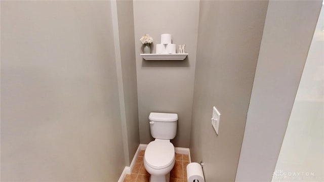 bathroom with baseboards, toilet, and tile patterned flooring