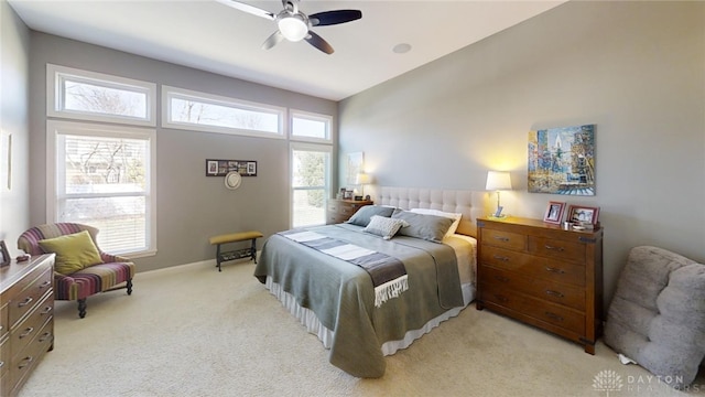 bedroom with a ceiling fan, multiple windows, light colored carpet, and baseboards