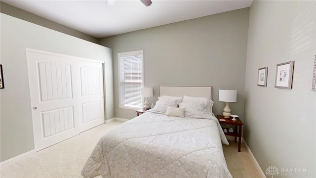 bedroom with a closet, baseboards, ceiling fan, and carpet flooring