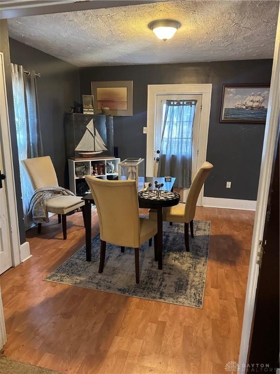 dining space featuring baseboards, a textured ceiling, and wood finished floors