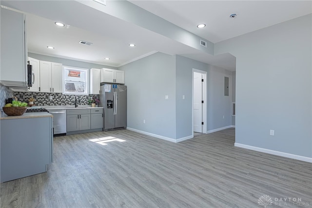 kitchen featuring visible vents, a sink, decorative backsplash, light countertops, and stainless steel appliances