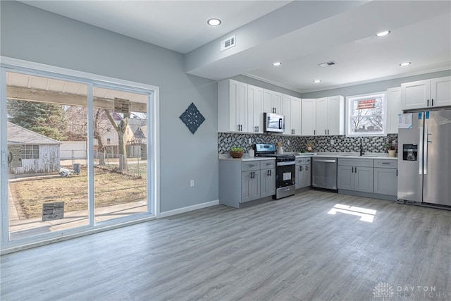 kitchen with tasteful backsplash, a healthy amount of sunlight, visible vents, and stainless steel appliances