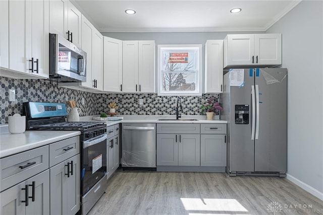 kitchen with tasteful backsplash, light wood-type flooring, appliances with stainless steel finishes, and a sink