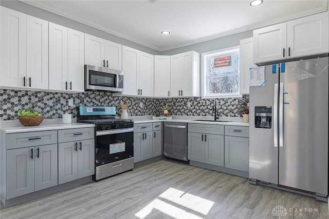 kitchen with gray cabinetry, a sink, tasteful backsplash, stainless steel appliances, and light countertops