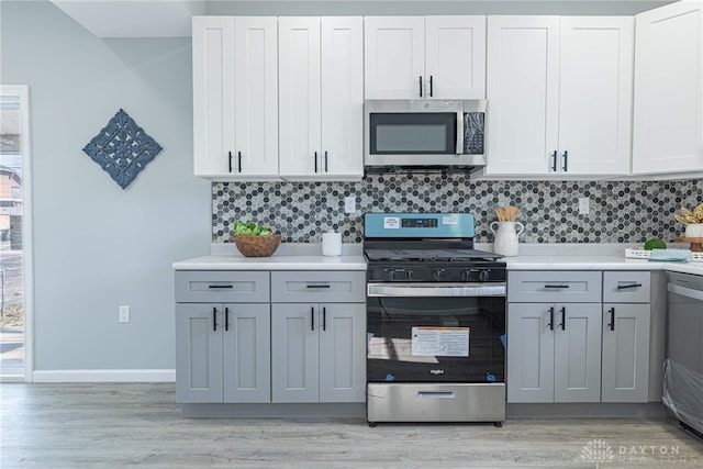 kitchen with light countertops, backsplash, light wood-style floors, and appliances with stainless steel finishes