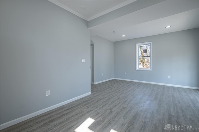 empty room with baseboards, ornamental molding, recessed lighting, wood finished floors, and arched walkways