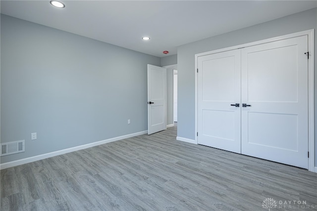 unfurnished bedroom featuring baseboards, visible vents, recessed lighting, a closet, and light wood-type flooring