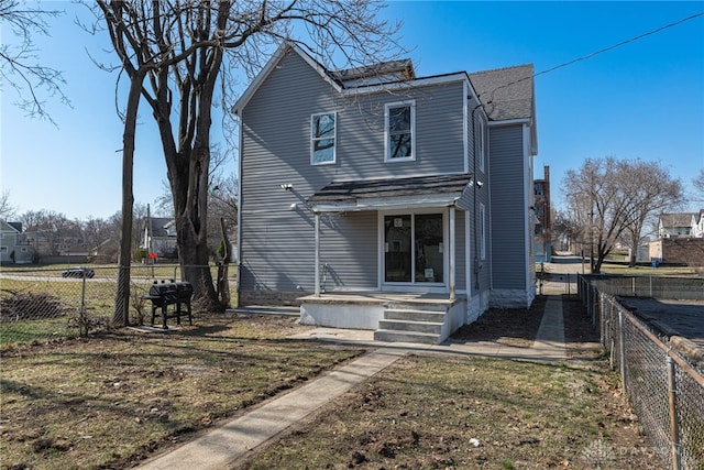 rear view of property featuring a fenced backyard and a shingled roof