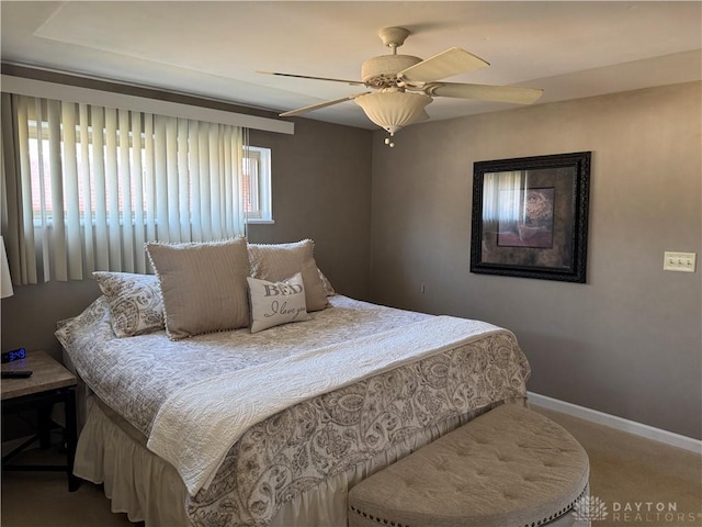 carpeted bedroom with ceiling fan and baseboards