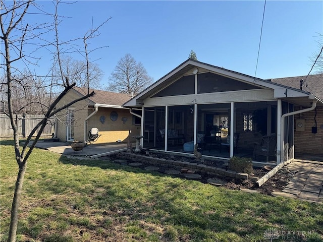 back of property featuring brick siding, fence, a lawn, a sunroom, and a patio area