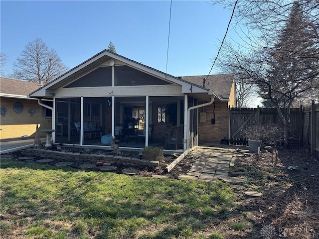 rear view of property with brick siding, fence, a lawn, and a sunroom