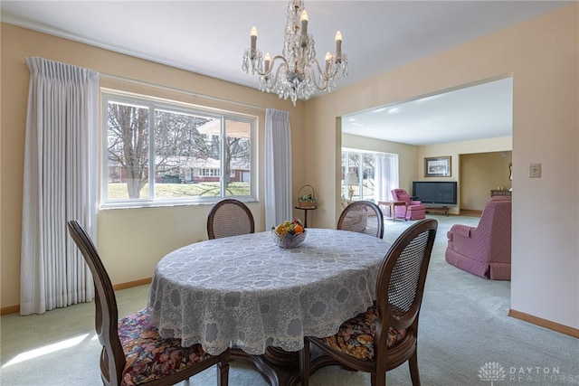 dining space with an inviting chandelier, carpet flooring, and baseboards