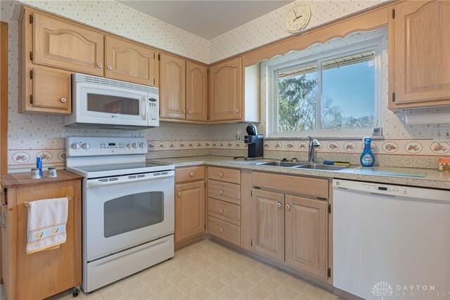 kitchen featuring a sink, wallpapered walls, white appliances, and light countertops