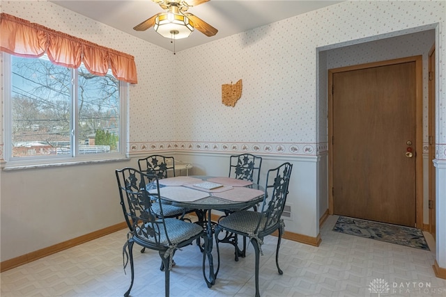 dining area featuring baseboards, light floors, ceiling fan, and wallpapered walls