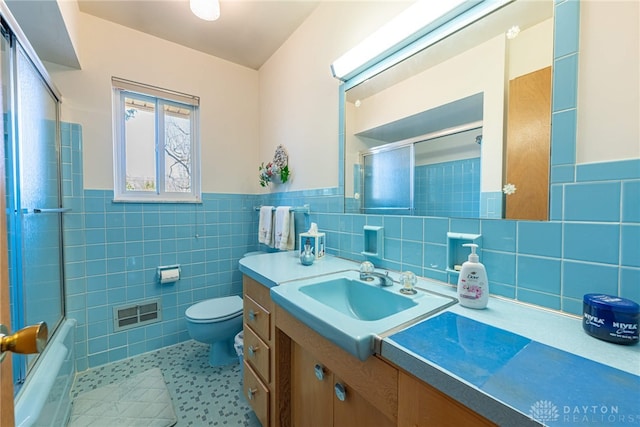 bathroom with a wainscoted wall, toilet, tile walls, tile patterned flooring, and vanity