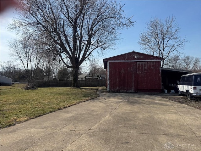 view of pole building with a garage, a lawn, fence, and driveway