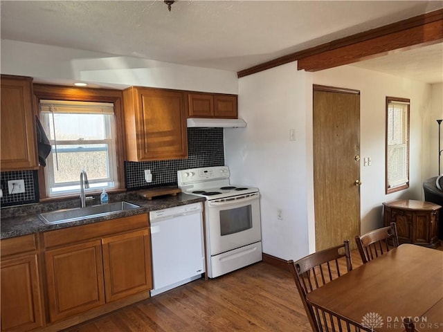 kitchen with white appliances, a sink, decorative backsplash, dark wood-type flooring, and brown cabinets