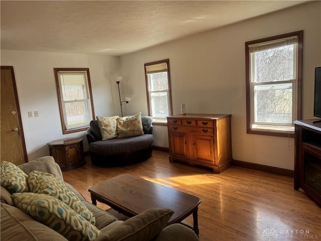 living room with light wood-style flooring, baseboards, and a textured ceiling