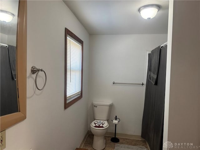 bathroom with a shower with shower curtain, toilet, baseboards, and tile patterned floors