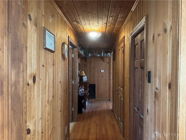 hallway featuring wooden walls, wooden ceiling, and wood finished floors