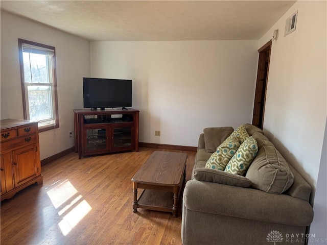 living room featuring baseboards, visible vents, and light wood-type flooring