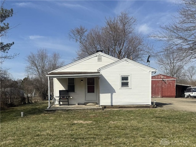 exterior space with a lawn, a porch, concrete driveway, and an outdoor structure