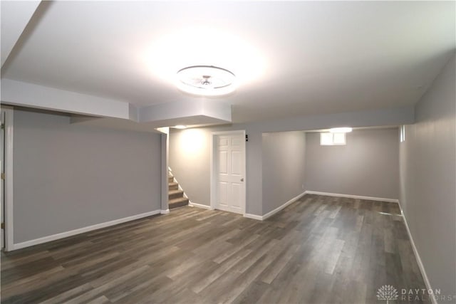 below grade area with baseboards, wood finished floors, and stairs