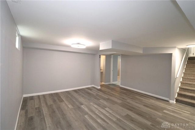 below grade area featuring baseboards, wood finished floors, and stairs