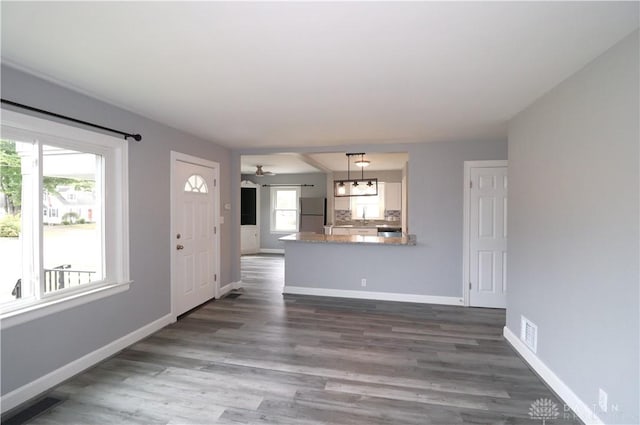 unfurnished living room featuring dark wood-style floors, baseboards, visible vents, a sink, and ceiling fan