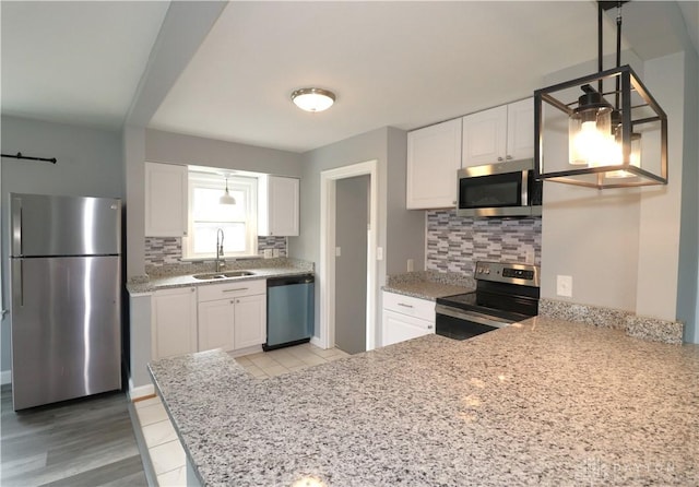 kitchen with backsplash, white cabinetry, stainless steel appliances, and a sink