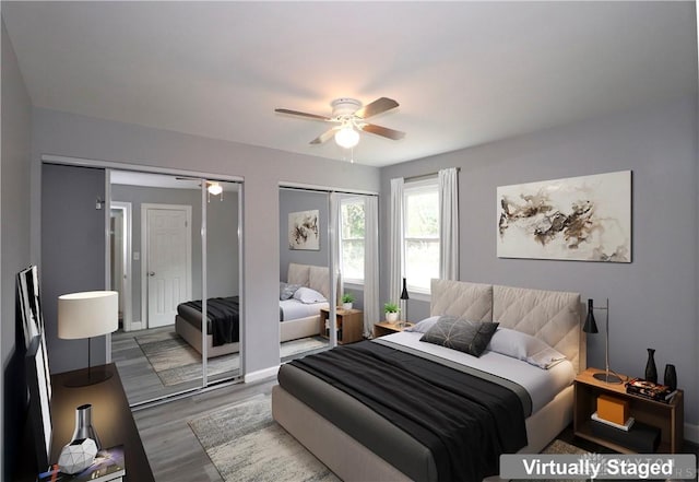 bedroom featuring multiple closets, baseboards, a ceiling fan, and wood finished floors