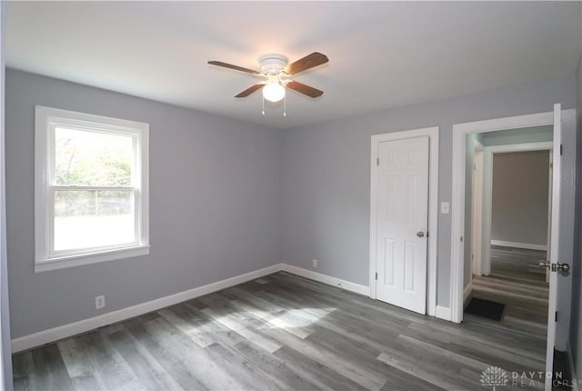 unfurnished bedroom with ceiling fan, baseboards, and wood finished floors