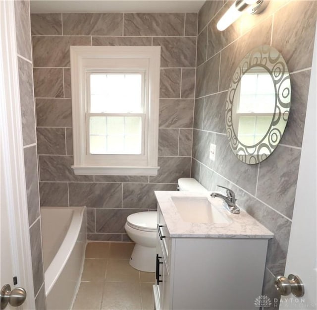 bathroom with vanity, tile patterned flooring, tile walls, toilet, and a washtub