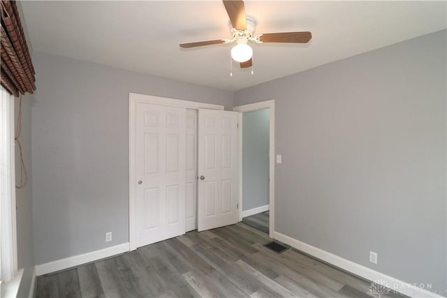 unfurnished bedroom with visible vents, ceiling fan, baseboards, wood finished floors, and a closet