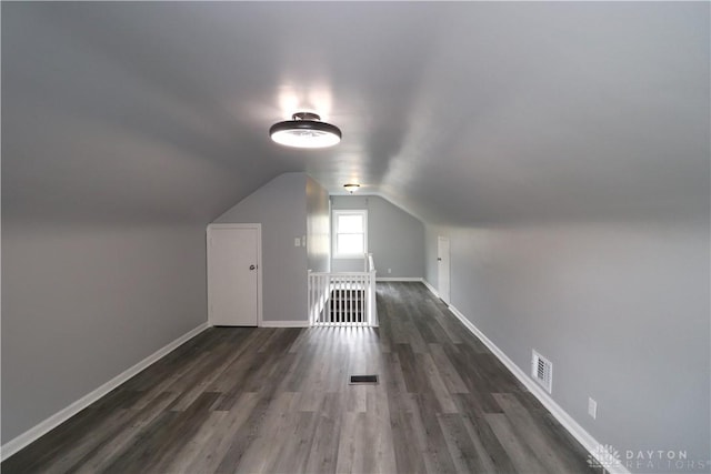 additional living space featuring visible vents, baseboards, lofted ceiling, and wood finished floors